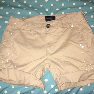 Tan mid length shorts with white paint splatter